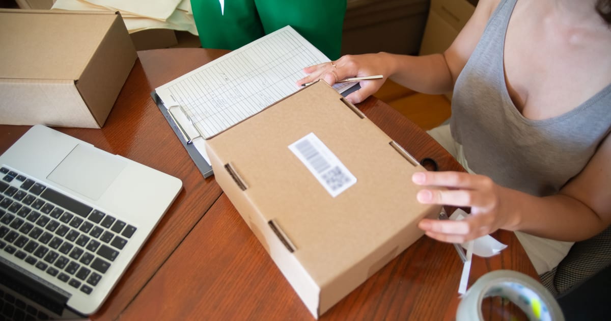 Vendedora empaquetando un pedido con la lista de clientes al lado: fidelizar clientes empieza por la post-venta