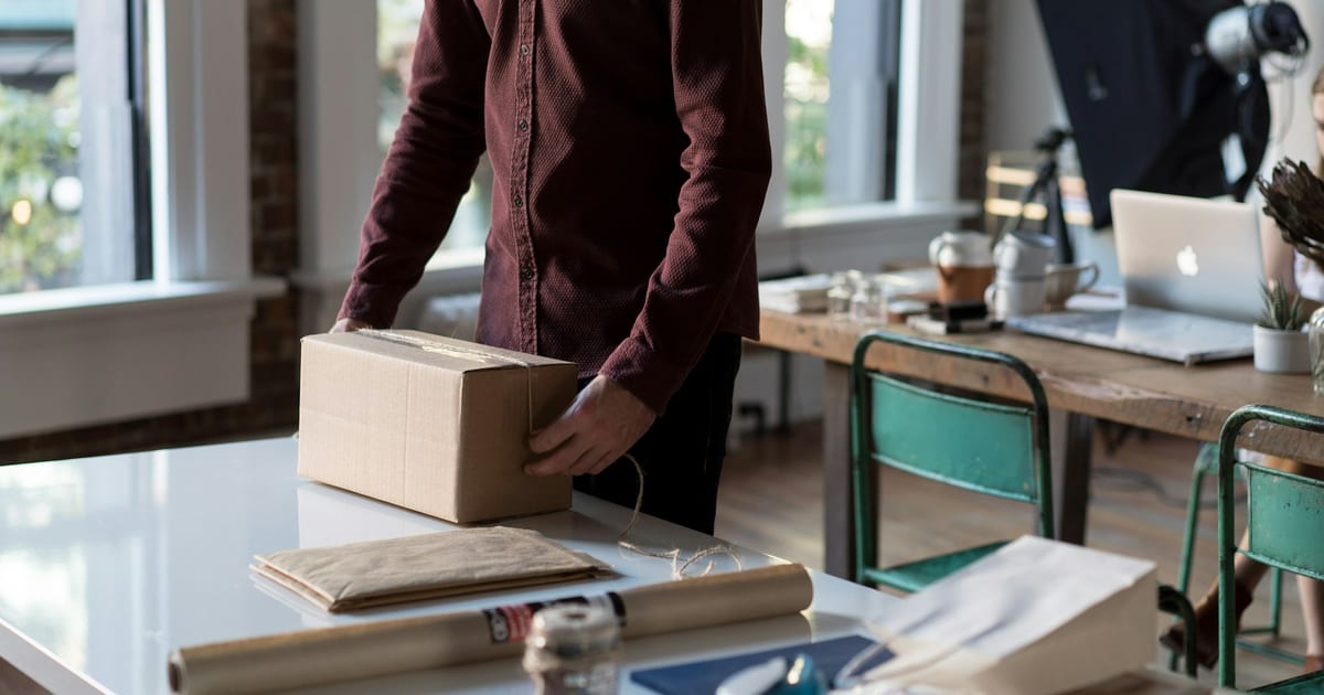 Vendedor embalando un pedido en una caja de cartón: generar confianza en los clientes empieza por cumplir lo que la tienda promete