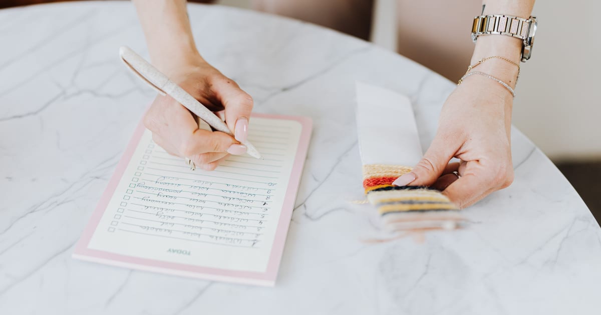 Persona anotando en una libreta los datos de un producto tejido para hacer la descripción de producto de su tienda