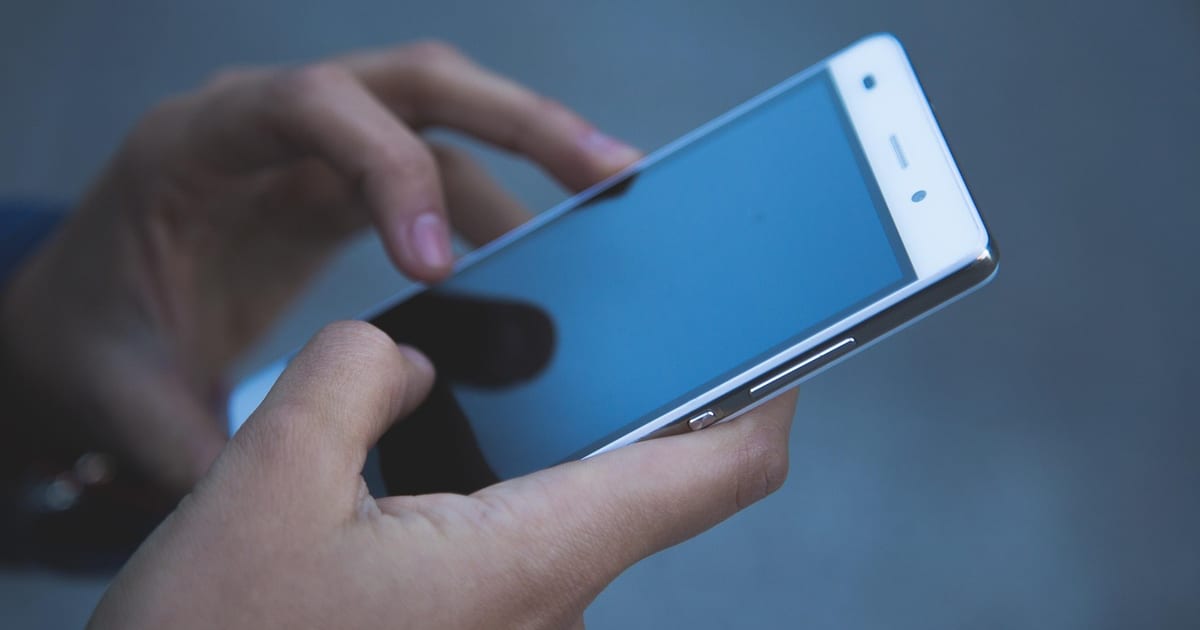 Manos usando el celular para vender por WhatsApp Business