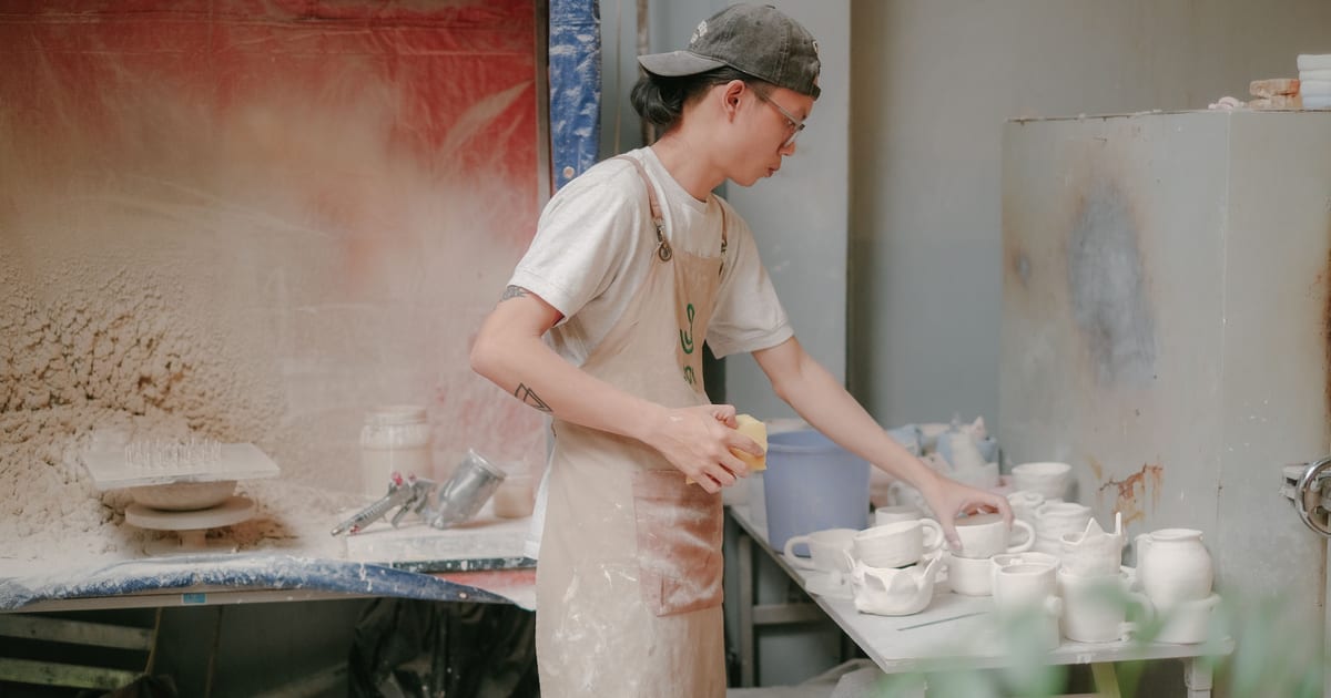 Ceramista trabajando en su taller con piezas hechas a mano sobre la mesa